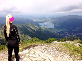 Rear view of woman standing on mountain against sky