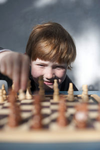 Smiling redhead boy playing chess