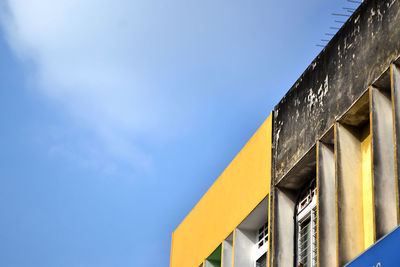 Low angle view of yellow building against blue sky