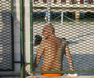 Rear view of woman standing by chainlink fence