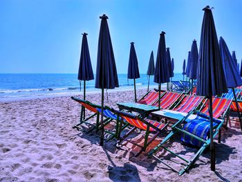 Deck chairs on beach against sky