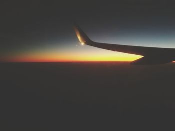 Airplane wing against sky during sunset