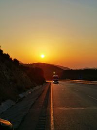 Cars on road against sky during sunset