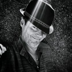 Close-up portrait of mature man wearing hat against concrete wall