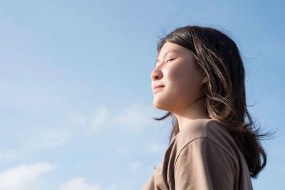 Low angle view of girl against blue sky