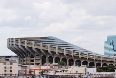 View of bridge in city against cloudy sky