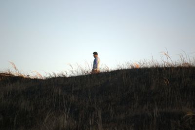 Mid distance view of man walking on field against sky