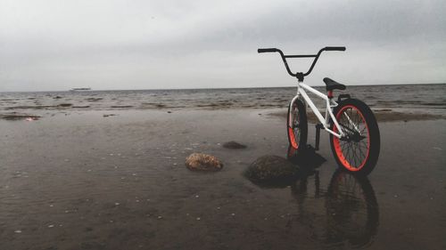 Bicycle on beach against sky