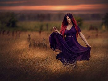 Portrait of woman wearing dress while standing on land during sunset