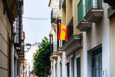 Low angle view of spanish flag hanging on building