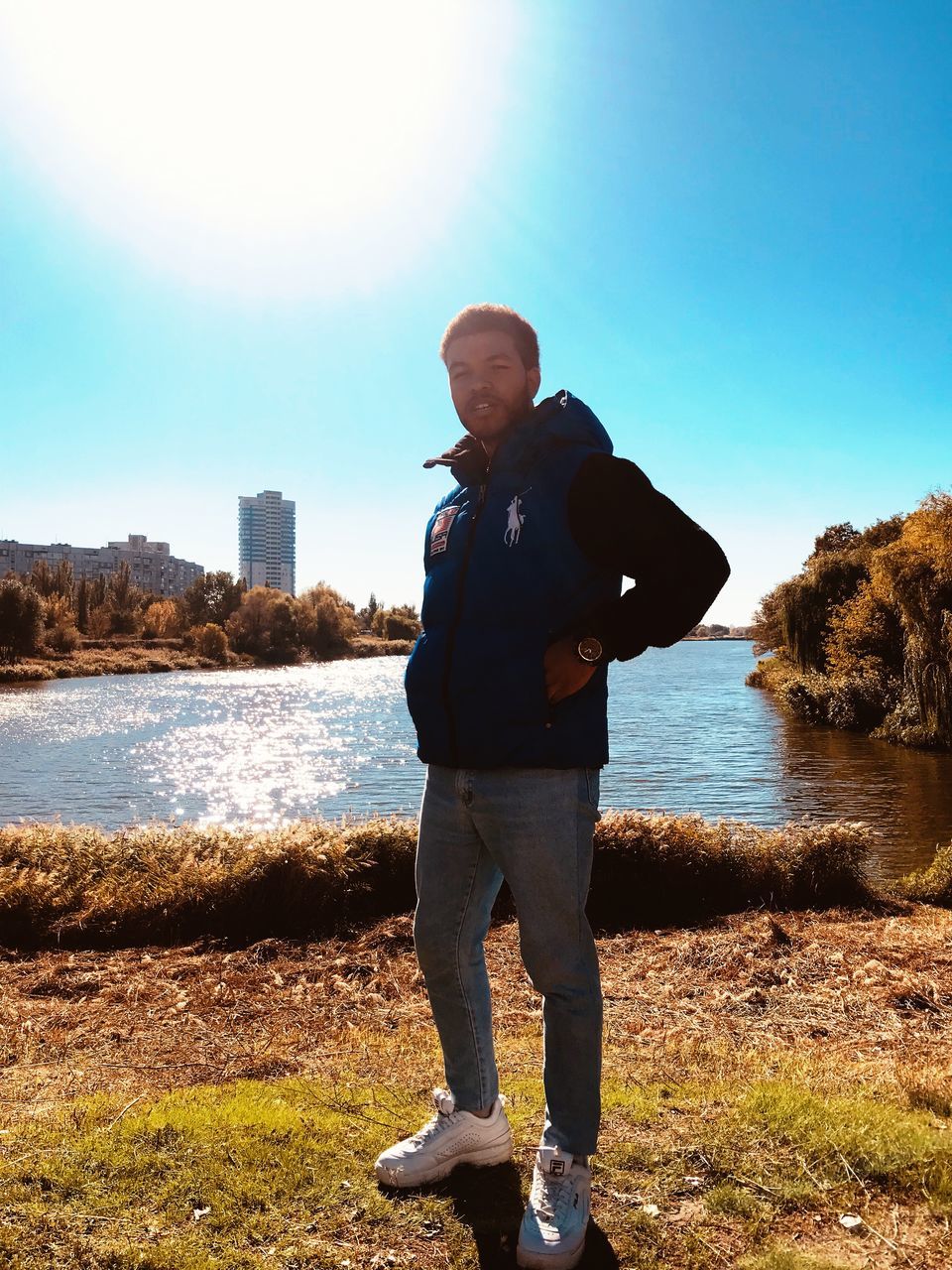 one person, water, standing, real people, sky, leisure activity, lifestyles, casual clothing, men, nature, full length, day, sunlight, beauty in nature, clear sky, lake, young adult, young men, outdoors