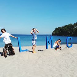 People at beach against clear blue sky