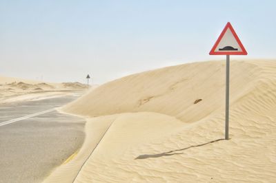 Road sign in desert against clear sky