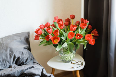 Huge bouquet of red tulips in a vase on the table.