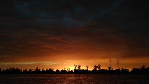 Silhouette of electricity pylon against sky during sunset