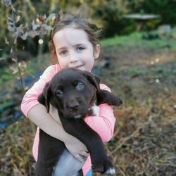 Portrait of cute girl with puppy on field