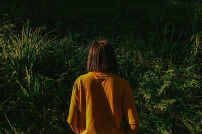 Rear view of woman standing on field in forest