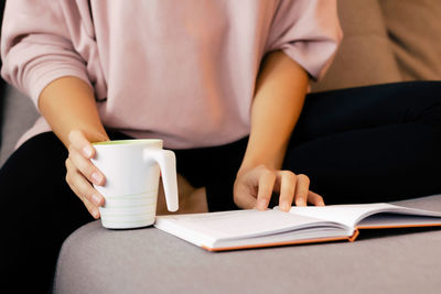 Midsection of woman holding coffee cup