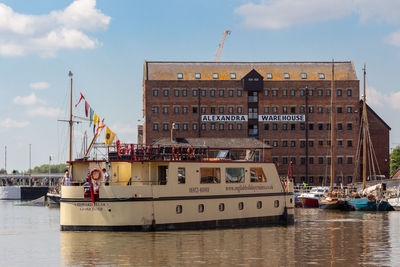 Sailboats moored on river by building against sky