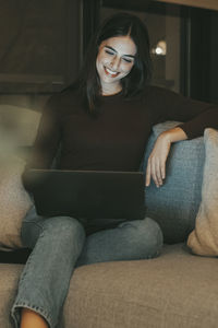 Portrait of young woman sitting on sofa at home