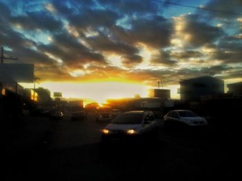 Cars on city street against cloudy sky