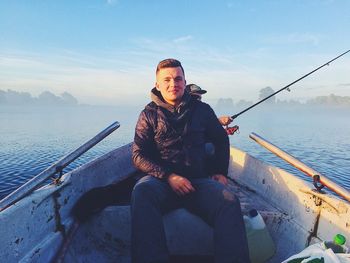 Low angle view of man sitting on boat in sea against sky during sunset