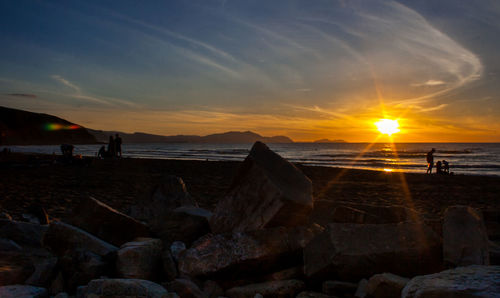 Silhouette man standing on beach against sky during sunset