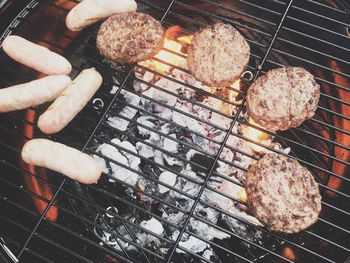 High angle view of patties and sausages on barbecue grill at yard