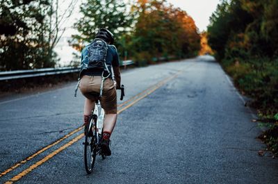 Rear view of young woman riding bicycle on road