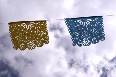 Low angle view of crochet flags hanging against sky