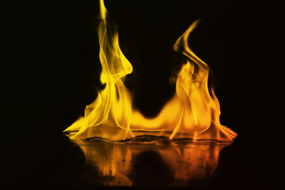 Close-up of burning candle against black background