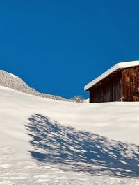 Snow covered land and houses against clear blue sky