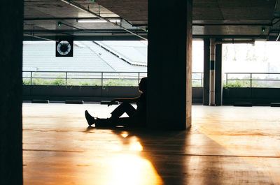 Silhouette man sitting on wooden floor