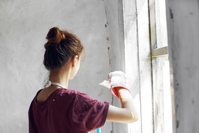 Rear view of woman standing against wall