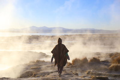 Person walking on land against sky