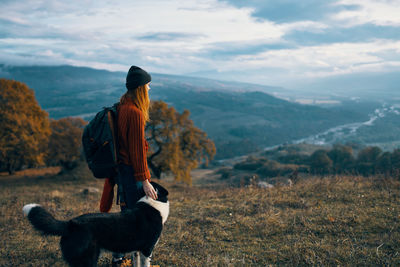 Rear view of woman with dog looking at mountains