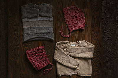 Children's wardrobe, knitted blouses and hats on a wooden background, the concept of autumn