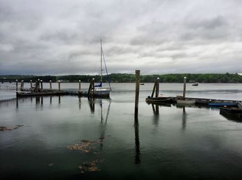 Boats in sea against cloudy sky