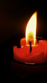 Close-up of lit candle in dark room