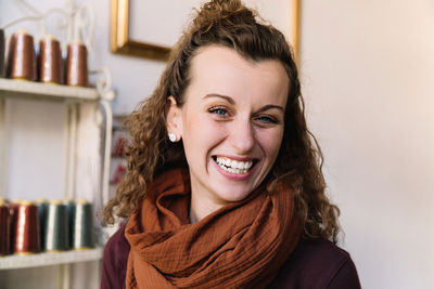 Joyful woman with curly hair and rust-colored scarf in a craft shop, store concept