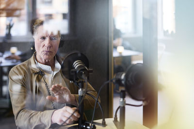 Mature man sitting and hosting podcast or radio show or podcast