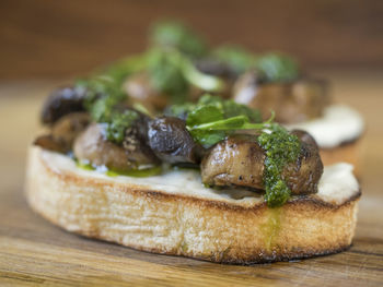 Close-up of bruschetta served with champignons and spinach on cutting board