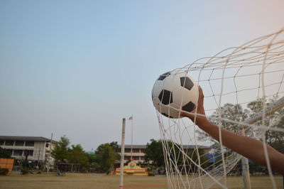 People playing soccer ball against clear sky