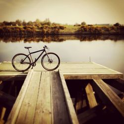 Bicycle parked on pier over lake