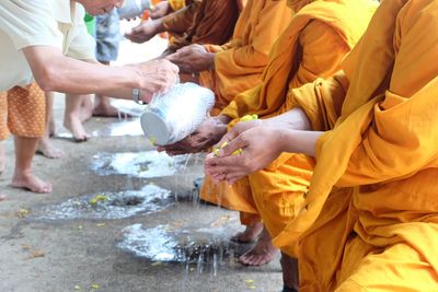 Man pouring water on monk hands outdoors