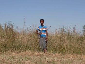 Portrait of boy standing on field against clear sky