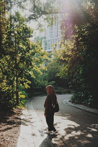 Woman walking on footpath amidst trees