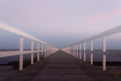 Footbridge over sea against sky