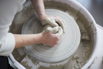 Cropped hands of woman molding pot in pottery class