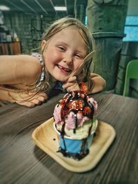 Portrait of smiling young woman holding dessert on table